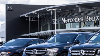 A Mercedes-Benz dealership featuring several parked black cars in front of a modern building.