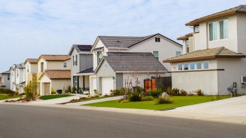 A row of modern houses featuring various architectural styles along a neatly paved street.
