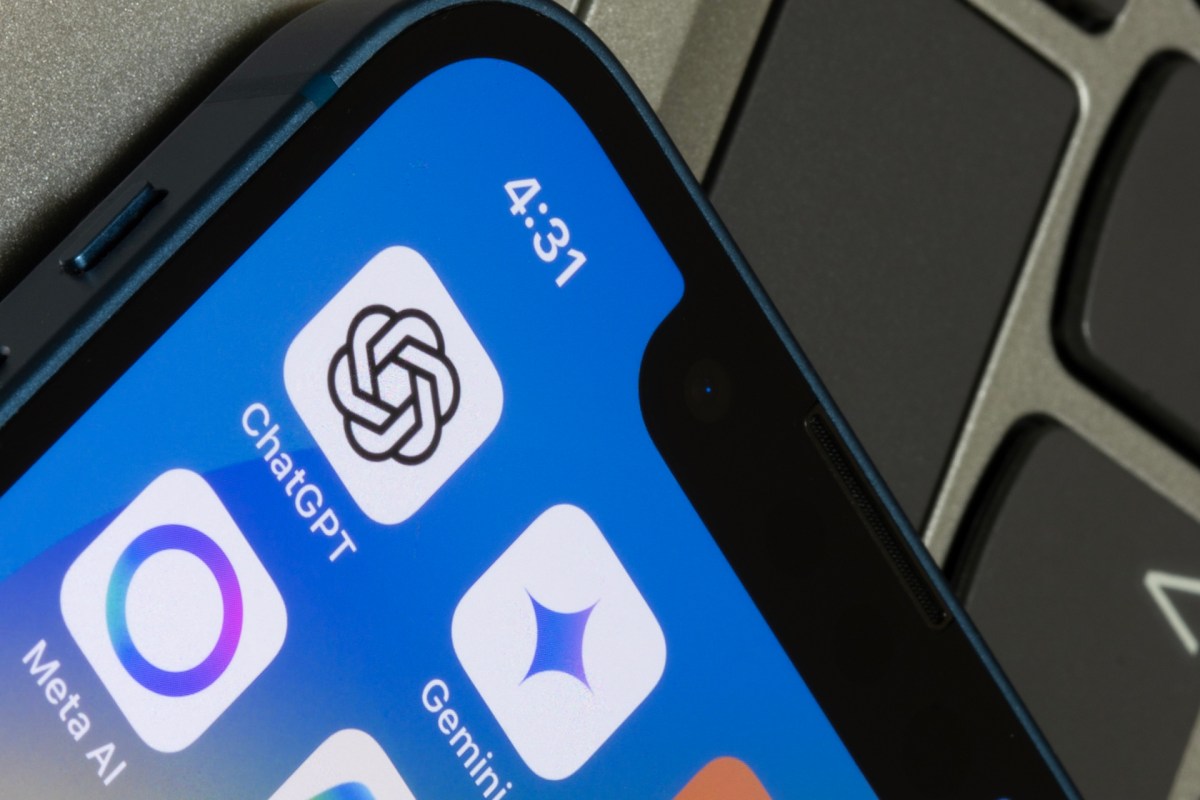 A close-up of a smartphone screen displaying the Meta AI app icon and other apps, on top of a computer keyboard.