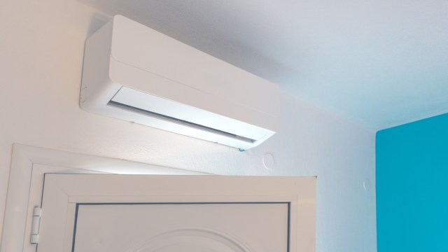 A modern, white air conditioner mounted on a wall above a door in an apartment.