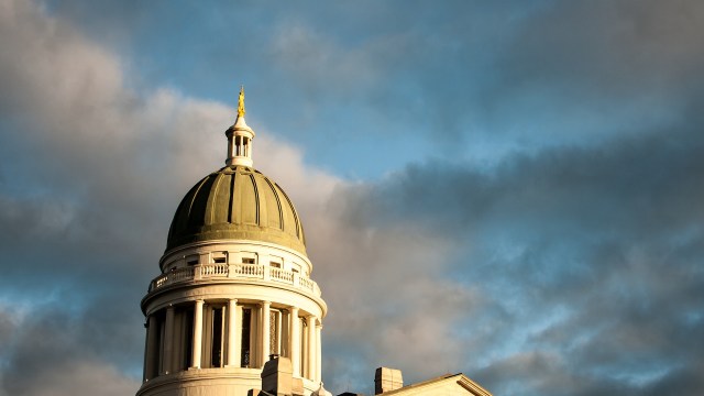 The dome of Maine's capitol building against a cloudy sky.