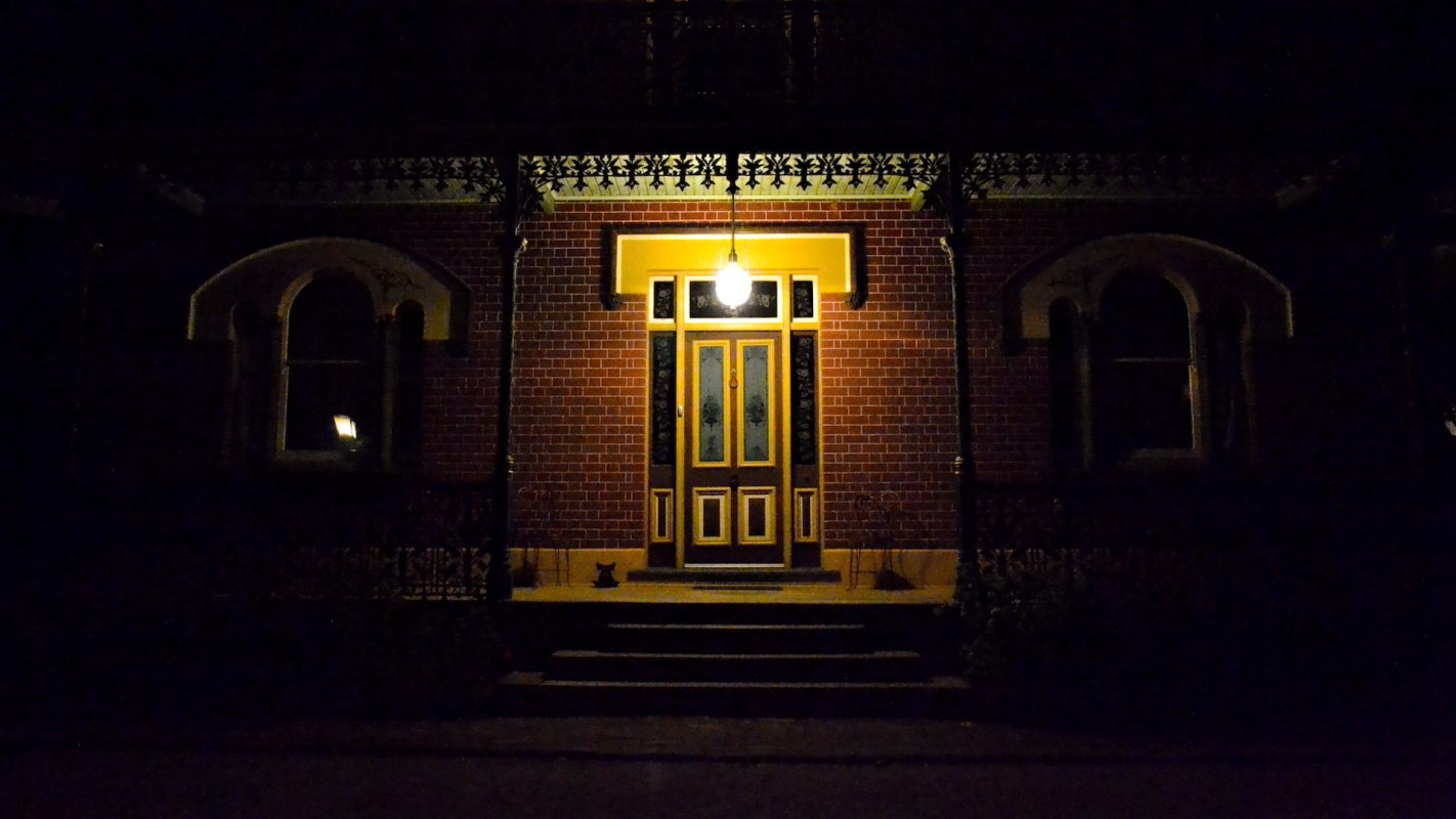 A warmly lit front door surrounded by dark surroundings.