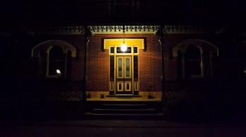 A warmly lit front door surrounded by dark surroundings.