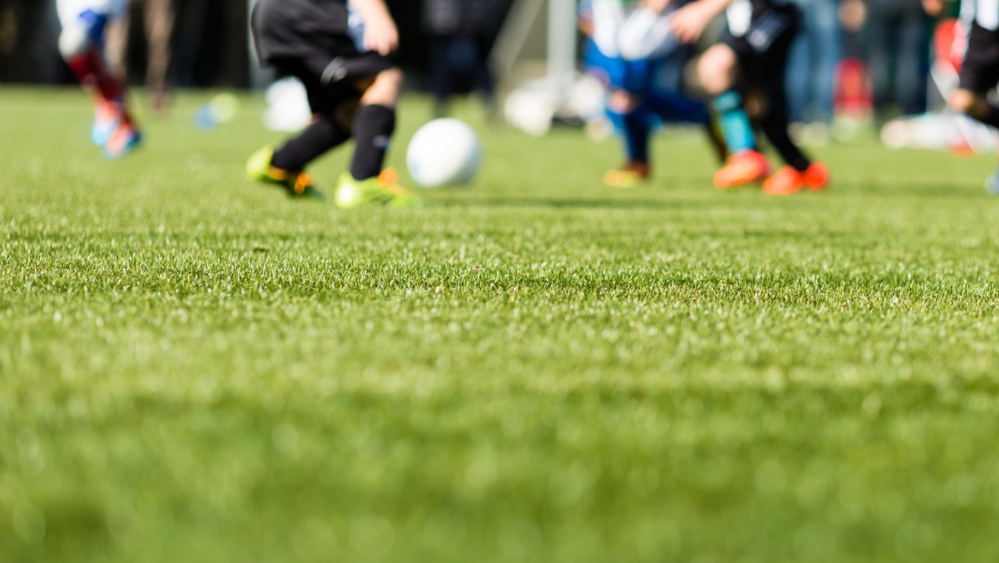 Players in motion on a soccer field, with a blurry focus on the artificial green grass.