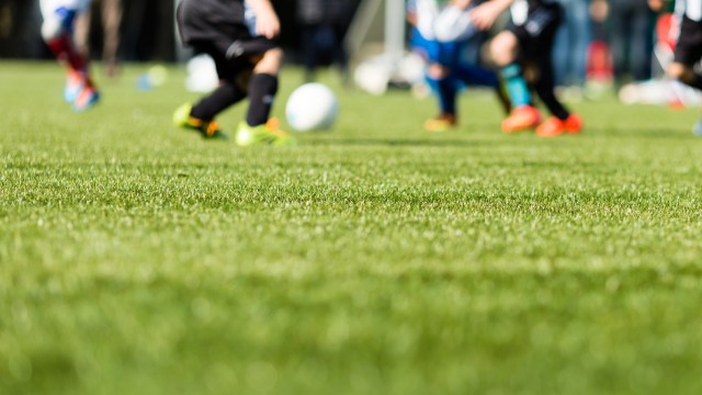 Players in motion on a soccer field, with a blurry focus on the artificial green grass.