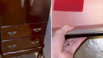 A close-up of a dark wooden cabinet with drawers, showing a hand reaching inside.