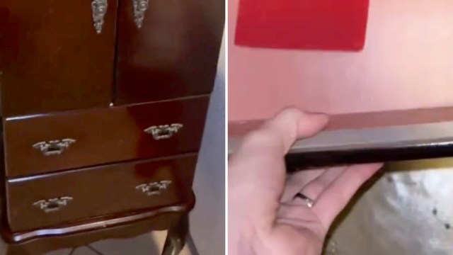 A close-up of a dark wooden cabinet with drawers, showing a hand reaching inside.