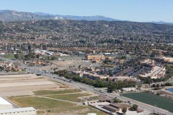 Aerial view of a California industrial site with highways, buildings, and mountains in the background.