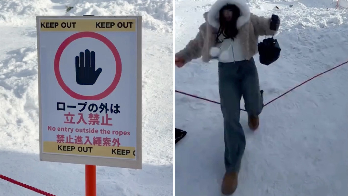 A woman in a winter outfit walks near a "Keep Out" sign on a snowy landscape.