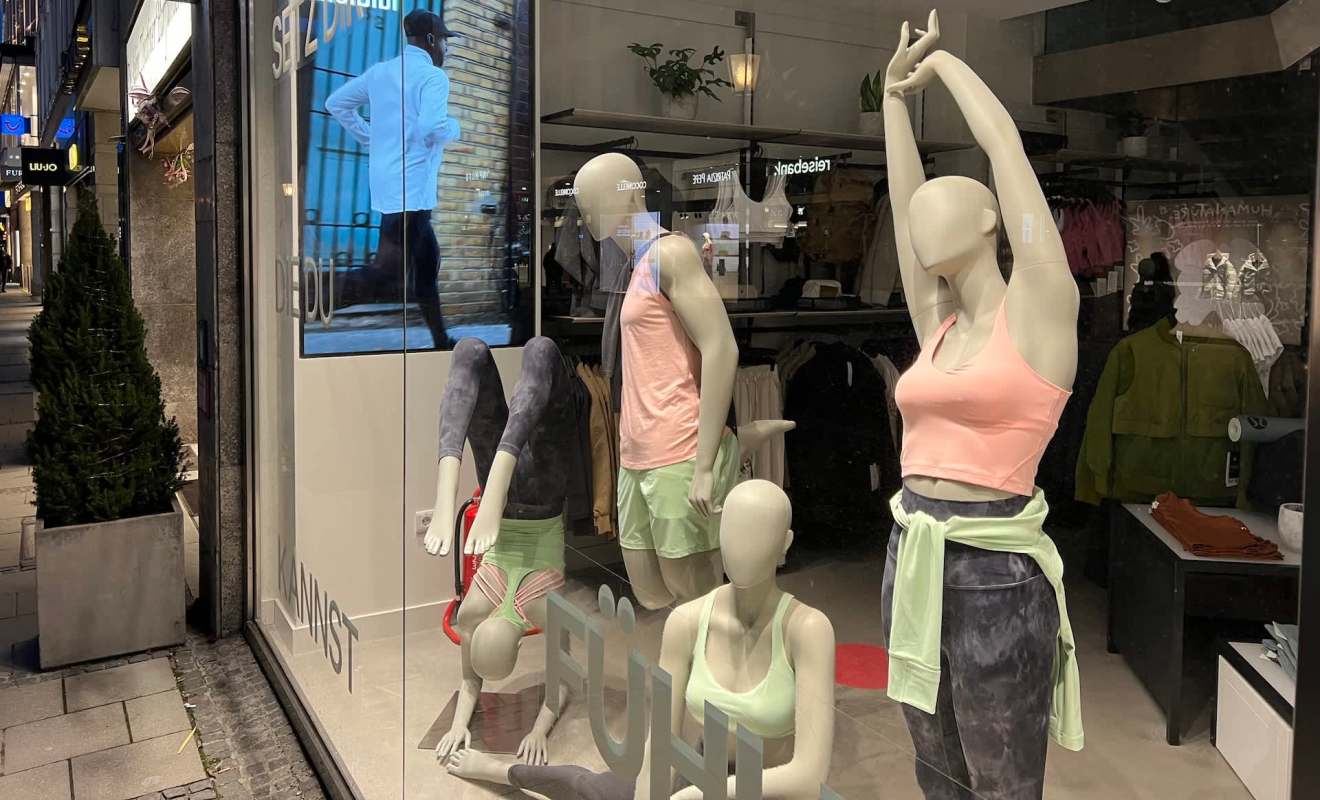 A display of athletic mannequins in a shop window, showcasing colorful workout attire and accessories.