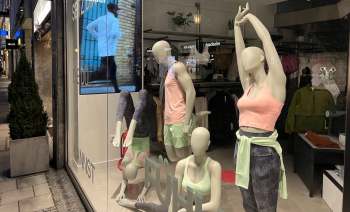 A display of athletic mannequins in a shop window, showcasing colorful workout attire and accessories.