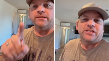 A man with a baseball cap gestures to a mini-split unit on a wall behind him while speaking in a room.