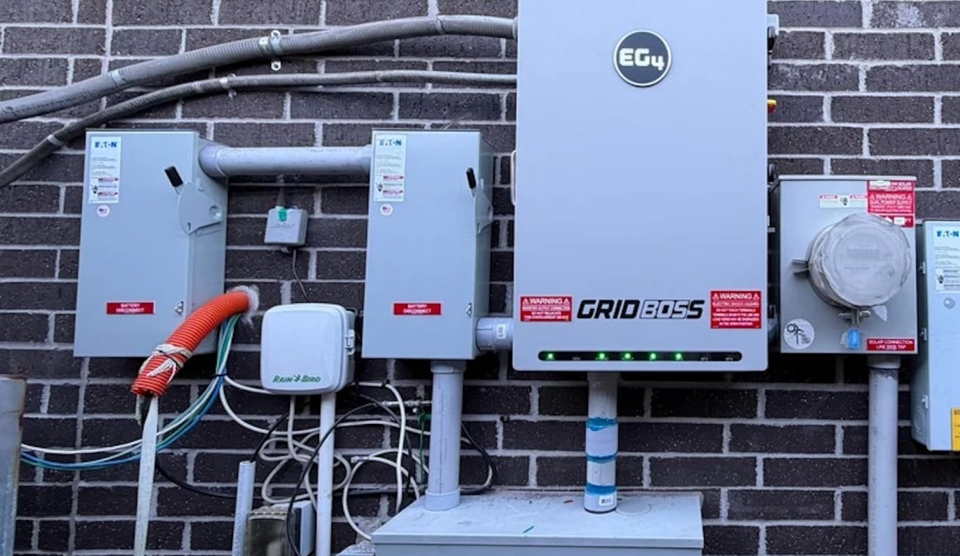A wall-mounted electrical setup featuring multiple panels, meters, and warning labels near a brick surface.