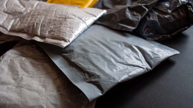 A close-up of various crumpled and sealed shipping envelopes on a dark surface.