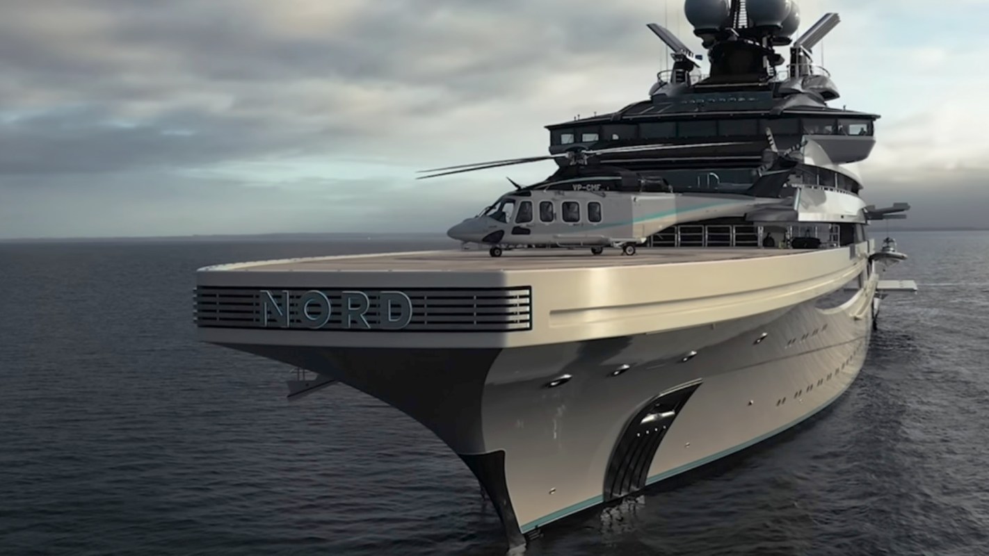 A luxurious superyacht named "NORD" with a helicopter on its deck, cruising in calm waters under a cloudy sky.