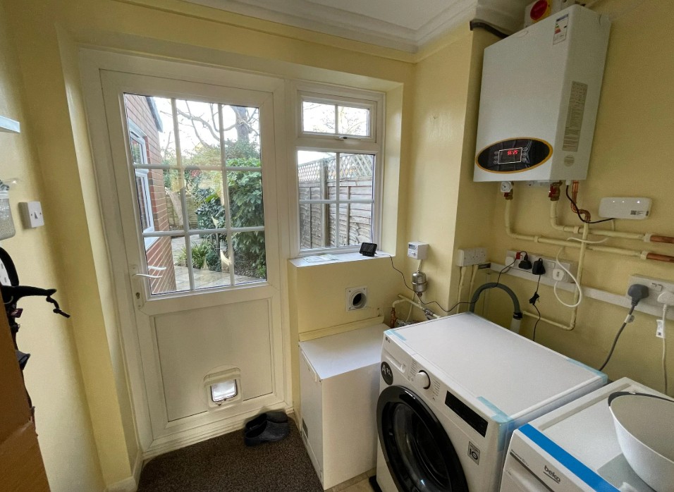 A bright room with a white door, a laundry machine, and an electric boiler.