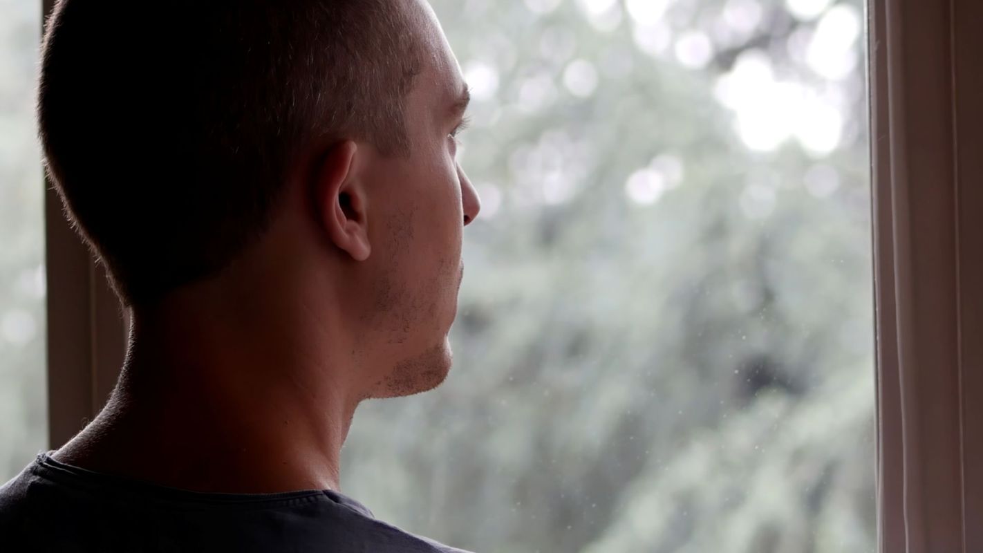 A person sadly looking through a window.