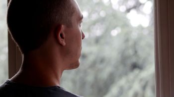 A person sadly looking through a window.