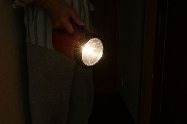Person holding a flashlight indoors during a power outage.