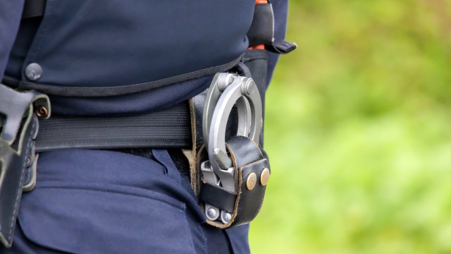 A close-up of a police officer's belt showing handcuffs secured in a leather holster.