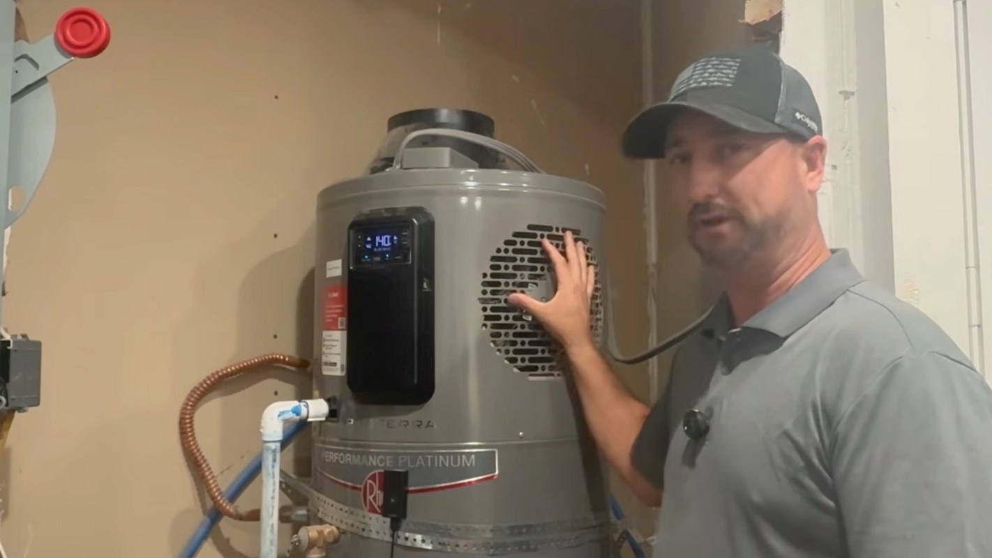 A technician demonstrates features of a Rheem hybrid heat pump water heater in a utility room.