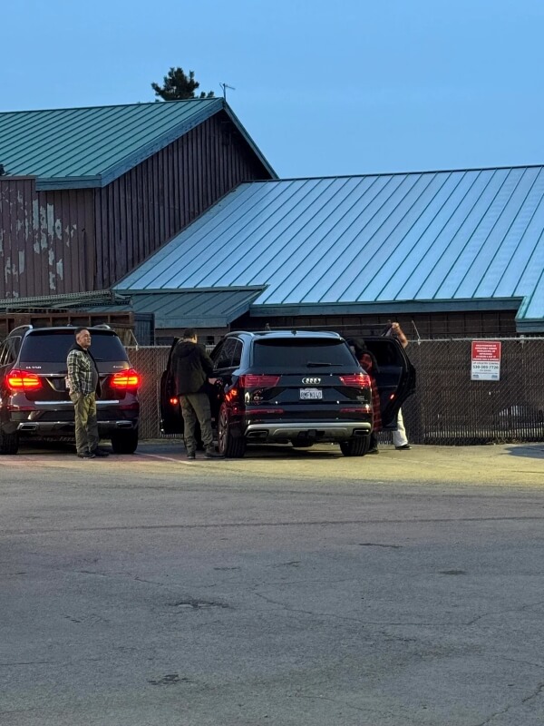 People getting into a vehicle in front of a building with their car doors open.