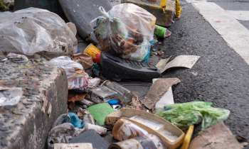 A cluttered street corner covered with various types of discarded trash and debris.