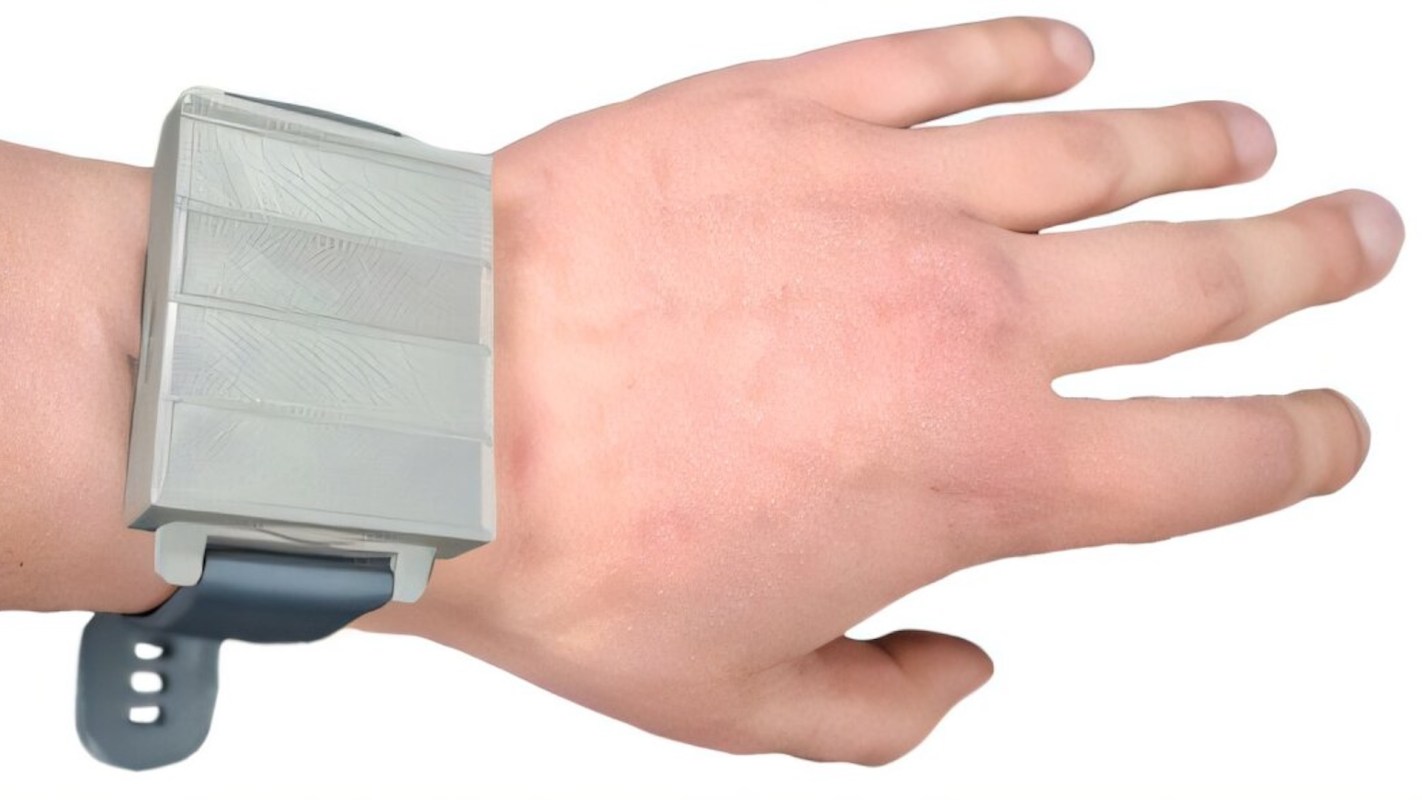 A hand with a large, rectangular, gray smartwatch-like device with a blue strap.