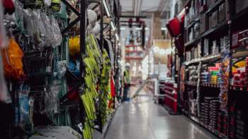 An organized aisle in a hardware store filled with safety gear and tools on display.