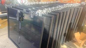 A stack of solar panels lined up vertically, showcasing their dark surfaces and connectors.