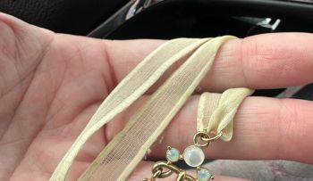 A hand holds up a Givenchy necklace.