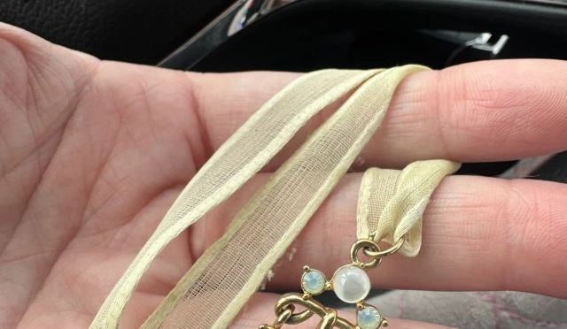 A hand holds up a Givenchy necklace.