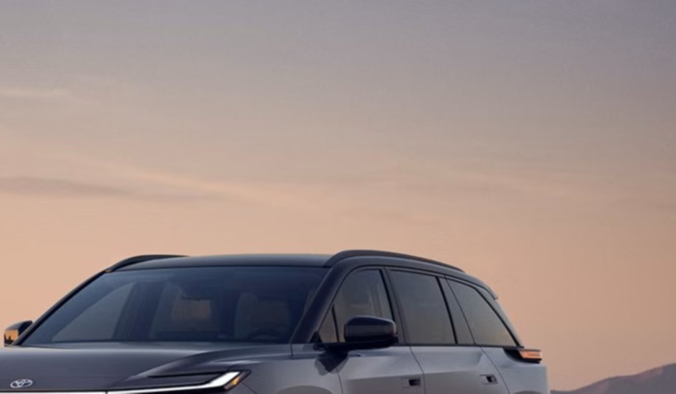 Top part of a Toyota Highlander electric SUV against a pastel sky.