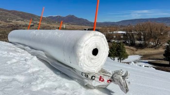 A ski resort snow farming by creating a large roll of snow.