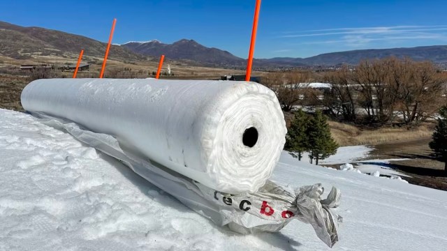 A ski resort snow farming by creating a large roll of snow.