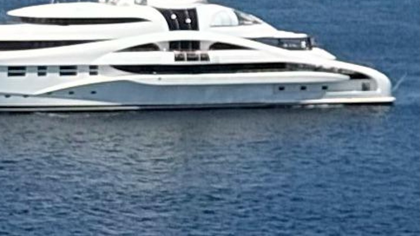 A sleek white yacht floating on calm blue waters.