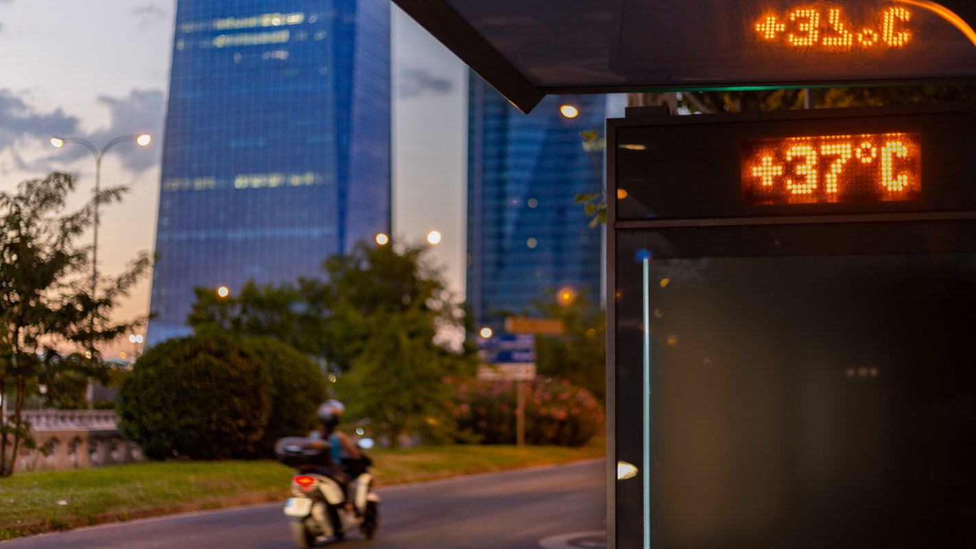 A bus stop with a display showing the temperature at 37°C.