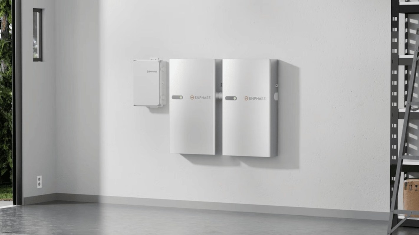 Two Enphase battery storage units mounted on a white wall in a well-lit room.