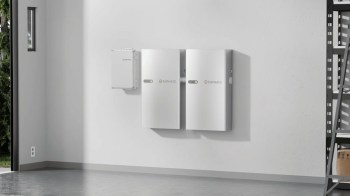Two Enphase battery storage units mounted on a white wall in a well-lit room.