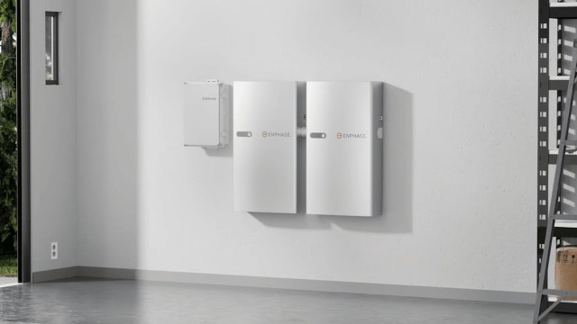 Two Enphase battery storage units mounted on a white wall in a well-lit room.