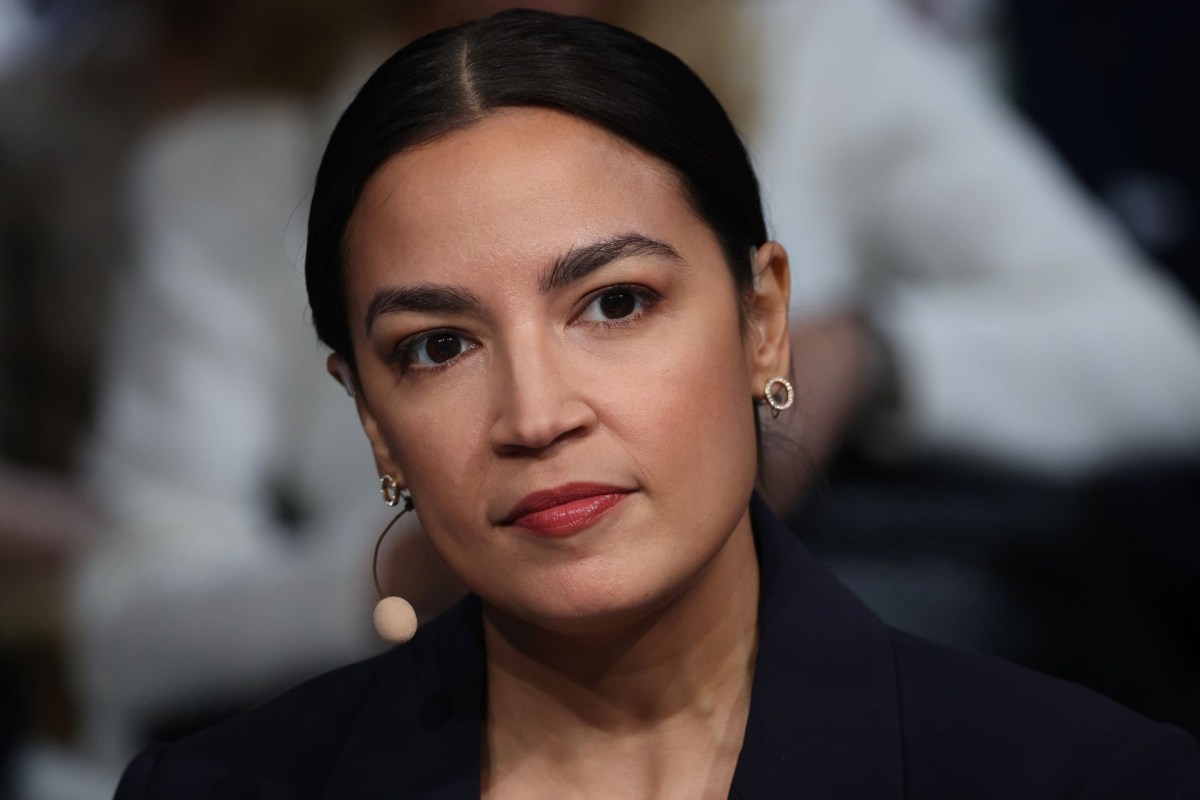 Alexandria Ocasio-Cortez, wearing a navy blazer and earrings.
