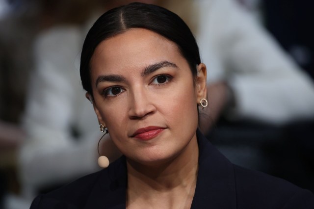 Alexandria Ocasio-Cortez, wearing a navy blazer and earrings.