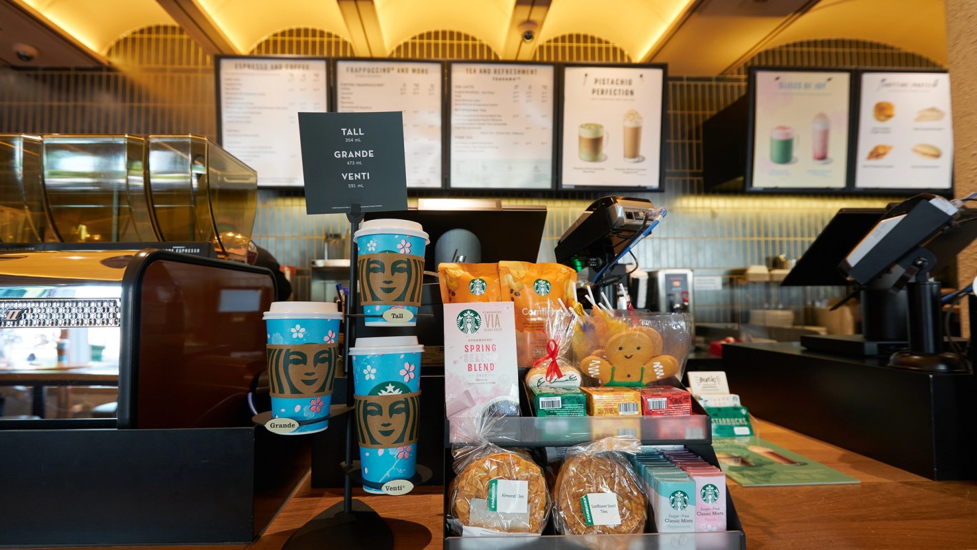 A Starbucks counter featuring cups, snacks, and a menu board.
