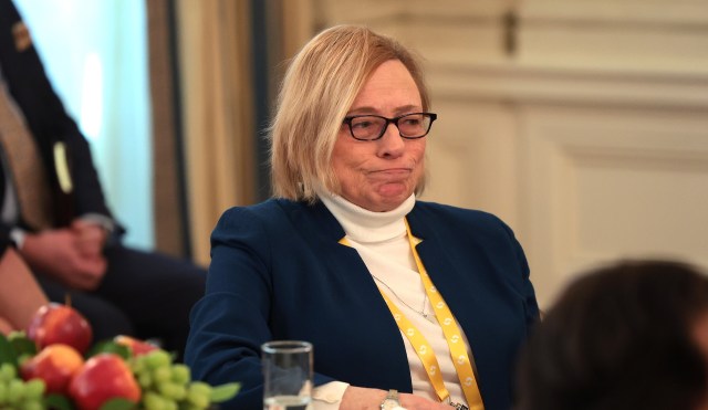Maine Governor Janet Mills, wearing glasses, looks contemplative while seated at a table with fruit, wearing a blue jacket.