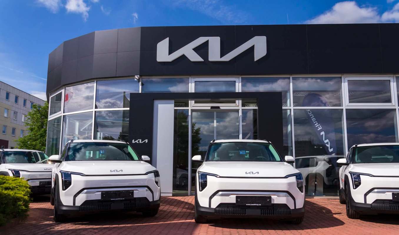 A Kia car dealership featuring several white vehicles displayed outside the modern showroom.
