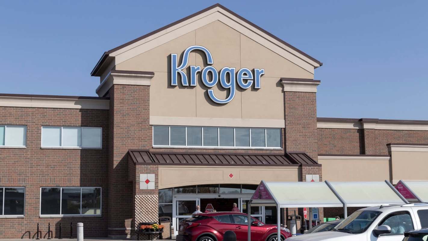 A Kroger grocery store exterior with clear skies and cars parked in front.