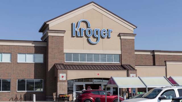 A Kroger grocery store exterior with clear skies and cars parked in front.