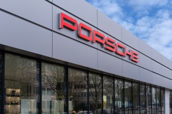 A Porsche dealership with a prominent red logo on a sleek, modern building exterior.