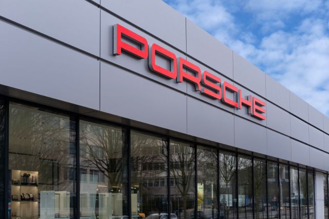 A Porsche dealership with a prominent red logo on a sleek, modern building exterior.
