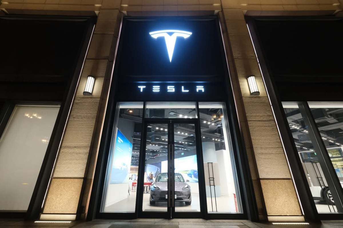 A Tesla showroom at night featuring a sleek car displayed behind large glass doors.